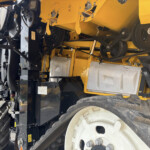 Close-up of a yellow industrial machine showing belts, gears, and drive components.