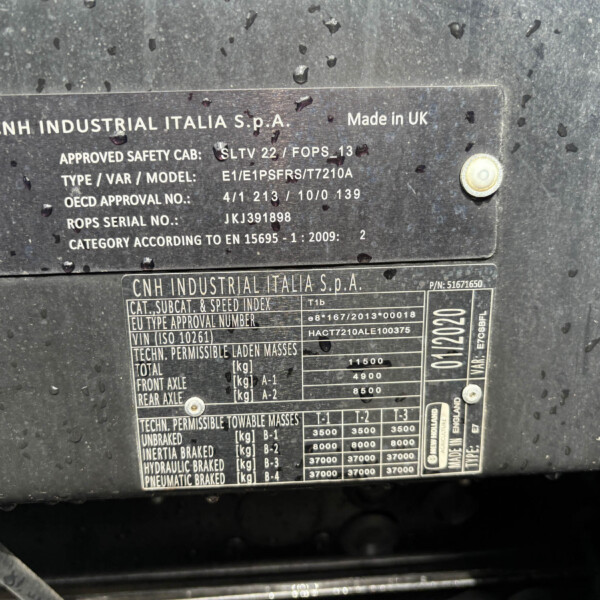 Metal identification plate on a dark, wet surface showing CNH Industrial Italia S.p.A. and Made in UK with model/approval details.