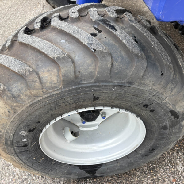 Close-up of a rugged off-road tire with deep, dusty tread.