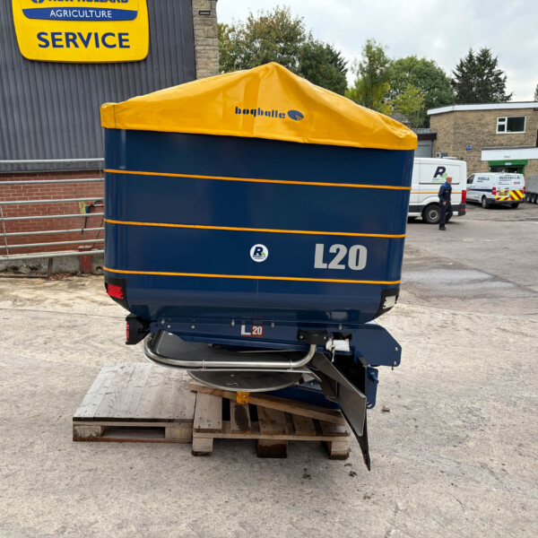 Blue L20 trailer with a yellow tarp cover resting on wooden pallets in a service yard.