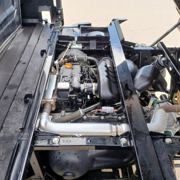 Close-up of a truck's engine bay with hoses, wiring, and metal frame inside the chassis.