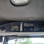 Interior of a truck cab showing the dashboard with climate controls, switches, and a circular air vent, viewed from the driver’s seat