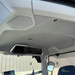 Interior view of a truck cab ceiling with an overhead speaker grille and dashboard controls visible near the windshield