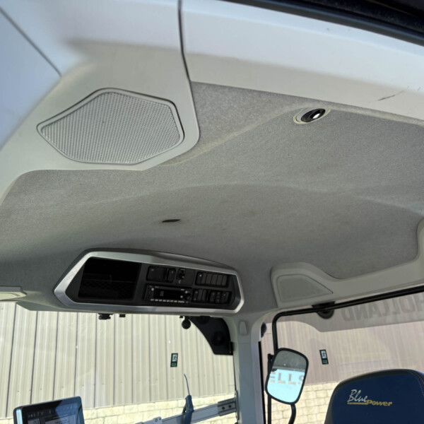 Interior view of a truck cab ceiling with an overhead speaker grille and dashboard controls visible near the windshield