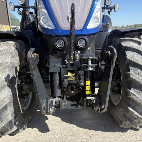 Front view of a blue agricultural tractor with oversized tread tires and dual headlights at the front center.