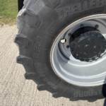 Close-up of a large tractor tire and wheel rim, showing heavy tread and bolted hub.
