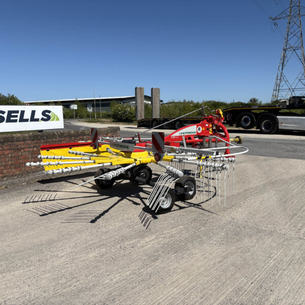 Farm equipment on a paved lot with a Russell's truck in the background and a brick wall in the foreground.