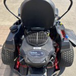 Rear/top-down view of a Toro ride-on lawn mower, showing the Kohler 7000 Series engine cover and dual control levers on either side.