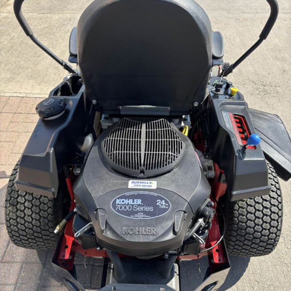 Rear/top-down view of a Toro ride-on lawn mower, showing the Kohler 7000 Series engine cover and dual control levers on either side.