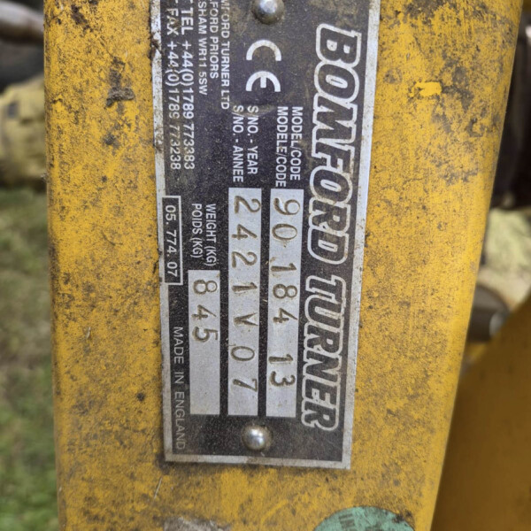 Close-up of a black-and-white machinery ID plate on yellow metal, showing model, serial numbers, weight and CE mark.
