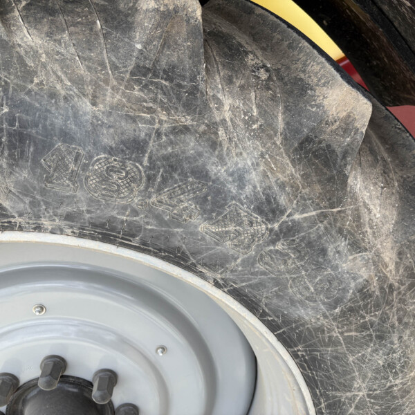 Close-up of a dusty vehicle wheel with a grey hub and black lug bolts showing wear on the tire surface.