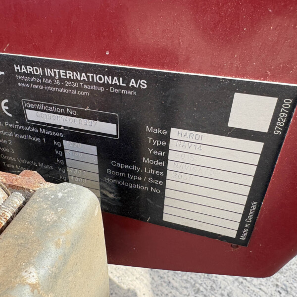 Close-up of a black identification plate on a red surface, reading HARDI INTERNATIONAL A/S and address information.
