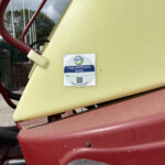 Close-up of yellow and red industrial machinery with a NSTS pass certificate sticker attached to the panel