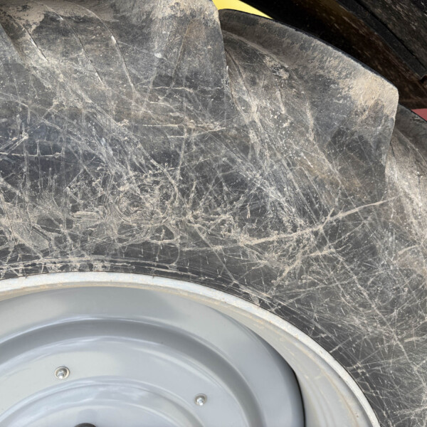 Close-up of a dusty tire and grey wheel rim, showing dirt, scratches, and mud on the surface.