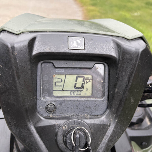 Close-up of a dusty motorcycle dashboard with a Honda logo and a digital speedometer showing 0 km/h.