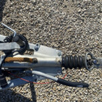 Tow hitch assembly with a coiled cable resting on a gravel surface.