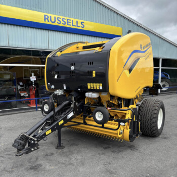 Yellow New Holland agricultural header on a tractor-like machine displayed outside the Russells store, with a large tire visible in the foreground.