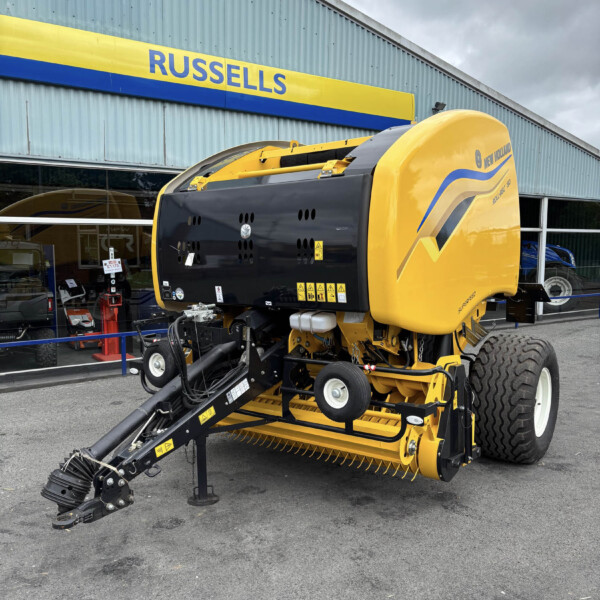 Yellow New Holland agricultural header on a tractor-like machine displayed outside the Russells store, with a large tire visible in the foreground.