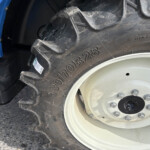 Close-up of a large off-road truck tire with a white wheel and blue fender in view.