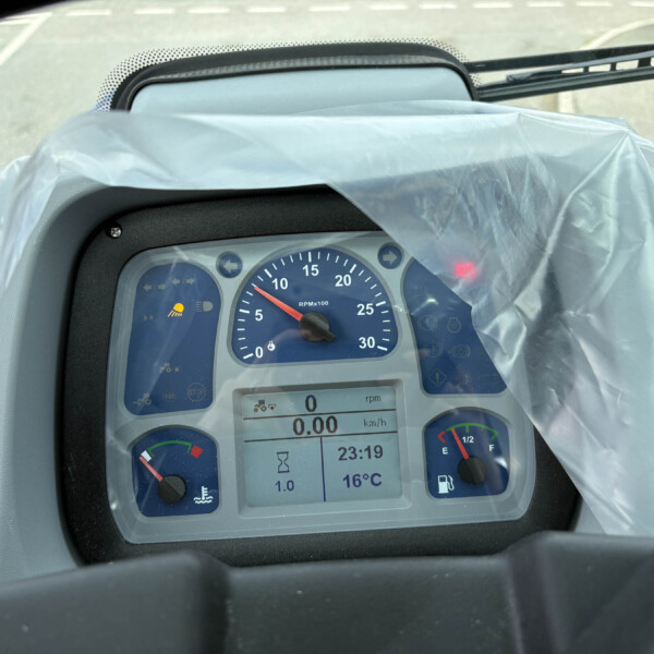 Close-up of a vehicle instrument cluster with RPM gauge, digital readouts, and warning icons under a transparent plastic cover