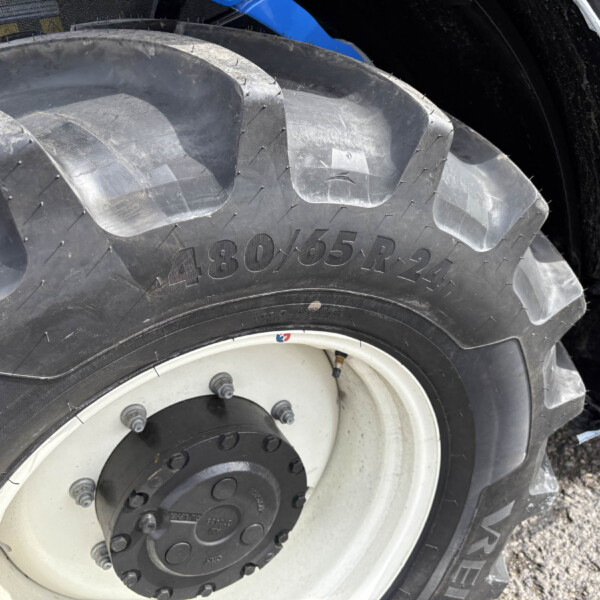 Close-up view of a large tractor tire with deep tread and white wheel rim; tire reads 430/65R24.