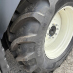 Close-up of a large truck tire with a white wheel, dirt and mud on the tire surface and rim visible.