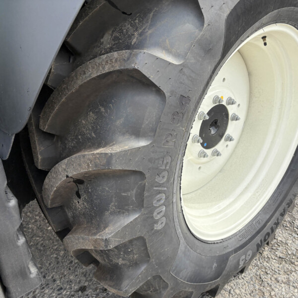 Close-up of a large truck tire with a white wheel, dirt and mud on the tire surface and rim visible.