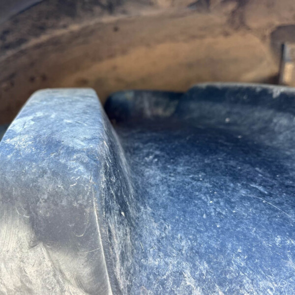 Close-up of a dusty blue metal surface with a rounded edge and scratches, possibly a railing or part of machinery.