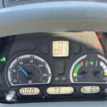Close-up of a vehicle dashboard showing the instrument cluster: speed at 0 km/h, tachometer near 0, digital readouts including 2288.3 and 73%, with several warning icons illuminated (parking brake, fuel/engine indicators).