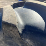 Close-up of dirty, dark plastic surface with curved ridges and a seam running through the center, dusty and worn.