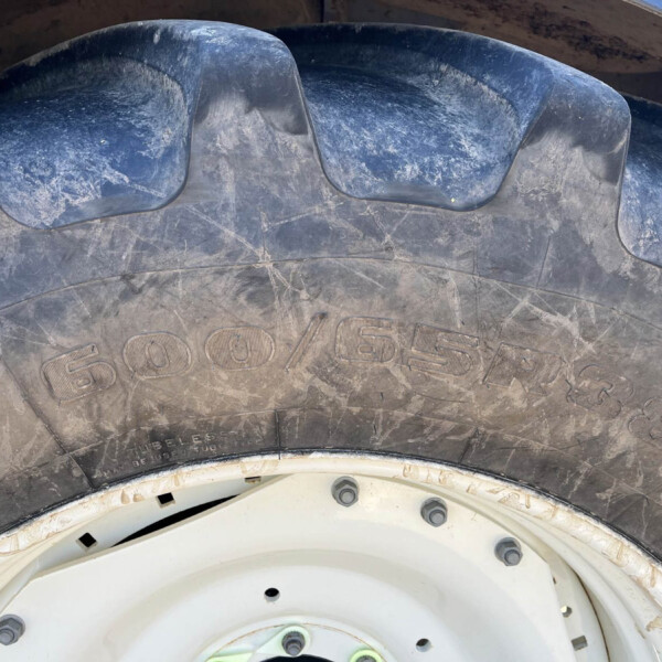 Close-up of a dusty vehicle tire showing deep tread blocks and a white wheel rim with dirt splatters.