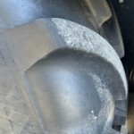 Close-up of a large rugged tire tread with signs of wear and dirt on the rubber surface.