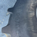Close-up of a black plastic automotive piece with raised numbers and a small emblem, lying on a dirt surface.