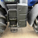Close-up of a heavy vehicle's vertical footstep ladder between large rubber tires, with dirt on the steps and body panels visible behind.