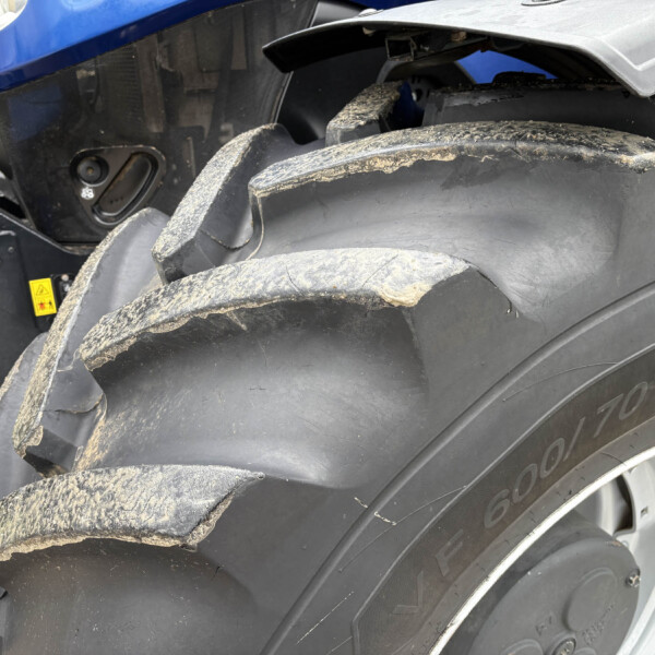 Close-up of a muddy tire with a torn fender on a large blue tractor-like machine, exposing the inner panel on the wheel side.