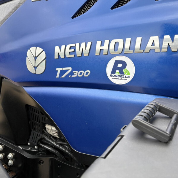 Blue New Holland T7.300 tractor hood with chrome branding and a Russell's dealer sticker visible on the side panel