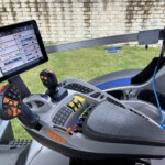 Cockpit of a heavy vehicle with a mounted tablet showing engine and system data, plus a joystick and controls.