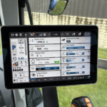Tablet mounted in a vehicle showing an on-screen diagnostic dashboard with engine hours, RPM, and various instrumentation panels for vehicle telemetry.