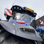 Close-up of a blue tractor front with a yellow license plate reading YX74 XXH and roof lights.