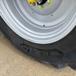 Close-up of a silver wheel/rim with black tire, showing yellow valve stems and lug bolts on a vehicle wheel well.