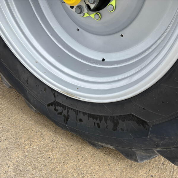 Close-up of a silver wheel/rim with black tire, showing yellow valve stems and lug bolts on a vehicle wheel well.