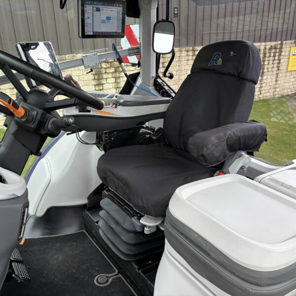 Bus driver’s cockpit with steering wheel, dashboard controls, and a mounted screen; black seat covers and interior components visible