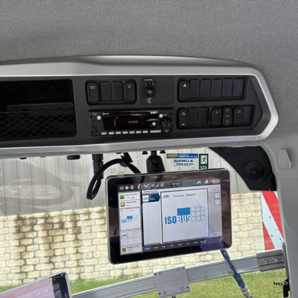 Interior of a vehicle cab with a central dashboard, touchscreen display, and row of switches under a gray overhead panel]**