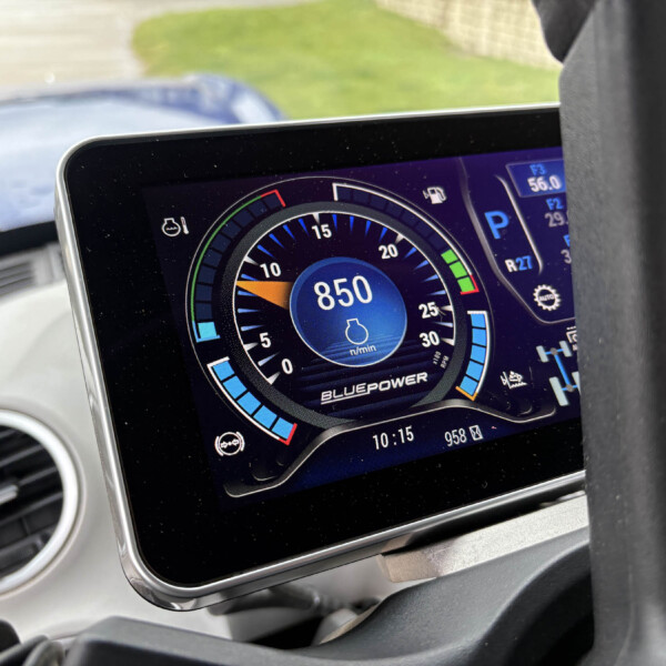 Close-up of a car's digital instrument cluster showing speed/RPM gauges with blue accents and a bluePower label on the screen inside the vehicle interior.