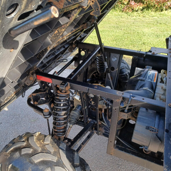 Close-up of a heavy-duty trailer suspension with a coil spring and rusted metal framework.