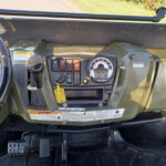 Dashboard of a green Polaris Ranger utility vehicle with steering wheel, ignition, control switches, and a large speedometer on the center console.