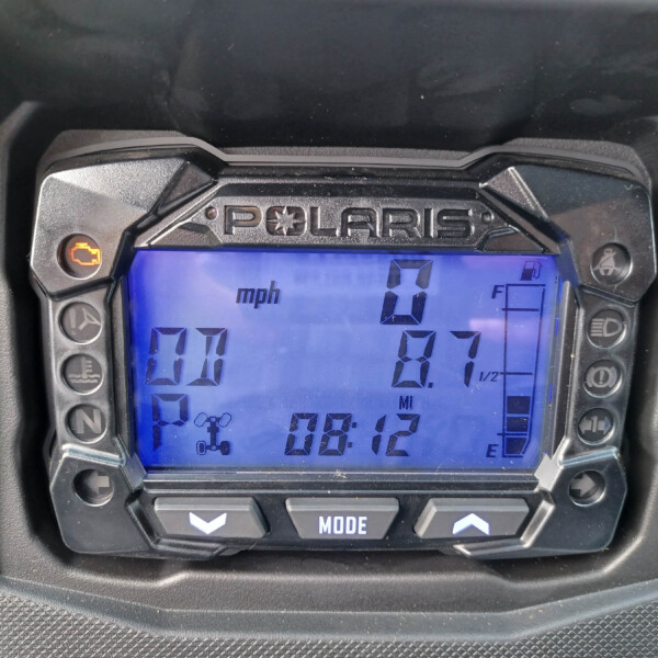 Digital instrument cluster showing speedometer at 0 mph on a Polaris gauge, with warning icon illuminated on the left and fuel gauge on the right.