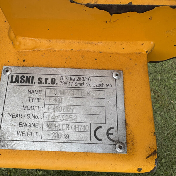 Close-up of a metal identification plate on orange industrial equipment, showing printed specifications and model/weight fields.