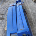 Blue metal industrial framework tied with a red strap, on a concrete warehouse floor.