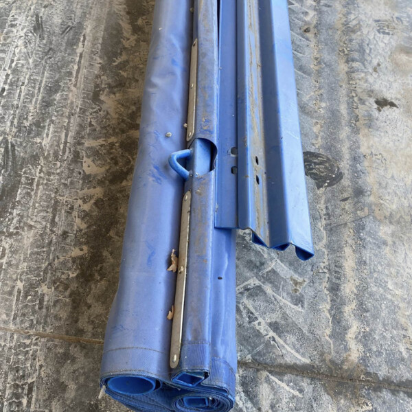 Blue folded scaffolding poles resting on a dusty workshop floor